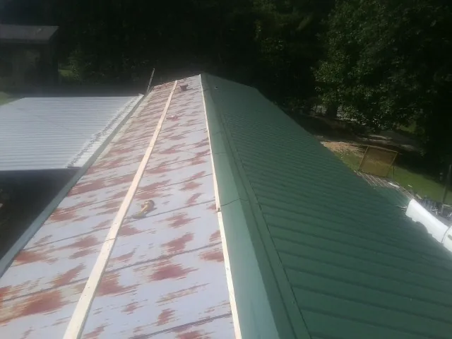 Old rusted panels beside newly installed green metal roofing — Wind Damage Roof Repair by Roofing Brothers in Valparaiso